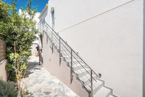Eine schmale Steintreppe führt zu einem weißen Gebäude mit Metallgeländer.