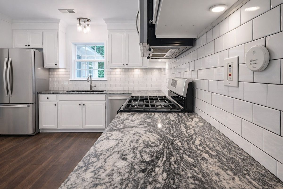 A modern kitchen with white cabinetry, a stainless steel refrigerator, a gas stove, and a built-in microwave.