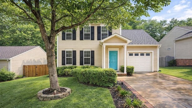 A two-story house with a front garage, a tree in the front yard, and a well-maintained lawn.