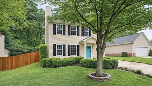 A two-story house with a front yard, a tree, and a blue door.