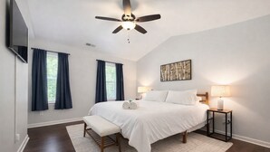 A bedroom with a bed, bedside tables, a ceiling fan, and a window with curtains.