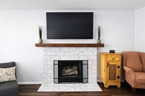 A living room with a fireplace, a television mounted above it, and a sofa.