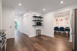 A modern kitchen with a stainless steel refrigerator, a microwave, and a trash can. There is a dining area with a table and chairs. - Sleeps 10 | 4BR w/ 6 Beds | Spacious Yard (Simpsonville)