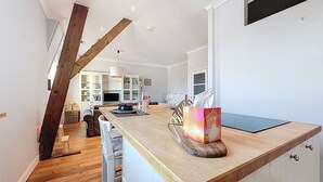Een moderne keuken met een houten eiland, witte kasten en een eethoek met stoelen.