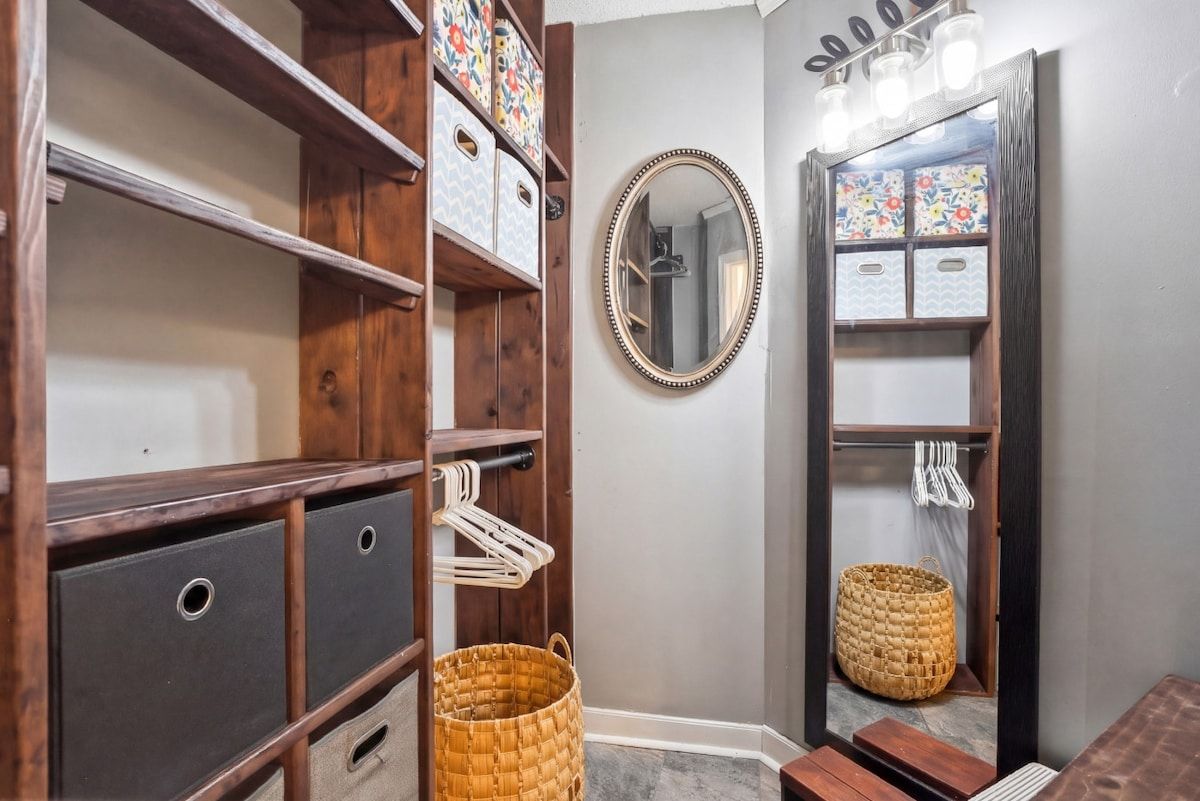 A bathroom with wooden shelving, a mirror, and storage baskets.