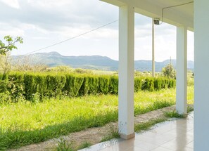 Ein überdachter Außenbereich mit Blick auf ein grünes Feld und Berge.