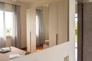 Ein Schlafzimmer mit einem Bett, einem Spiegel und einem Fenster mit Vorhängen.