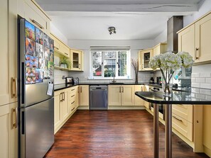 Une cuisine dotée d’un plancher en bois, d’appareils électroménagers en acier inoxydable et de meubles de couleur claire.