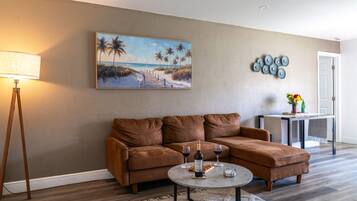 Spacious Open-Concept Living Room: Unwind in luxury on this plush brown sectional sofa, framed by a stylish tripod floor lamp, coastal-inspired wall art, and an open layout that connects seamlessly to the dining space.