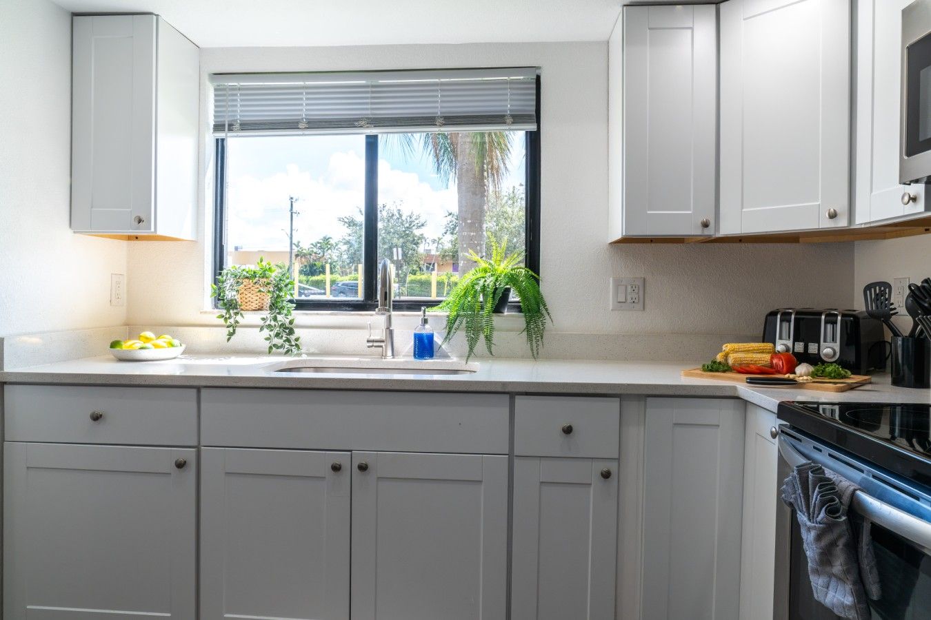 Bright & Fully Equipped Chef`s Kitchen: Cook your favorite vacation meals with ease in this light-filled chef`s kitchen, showcasing modern stainless steel appliances, pristine white cabinetry, an over-the-range microwave, deep double sink, and expansive p