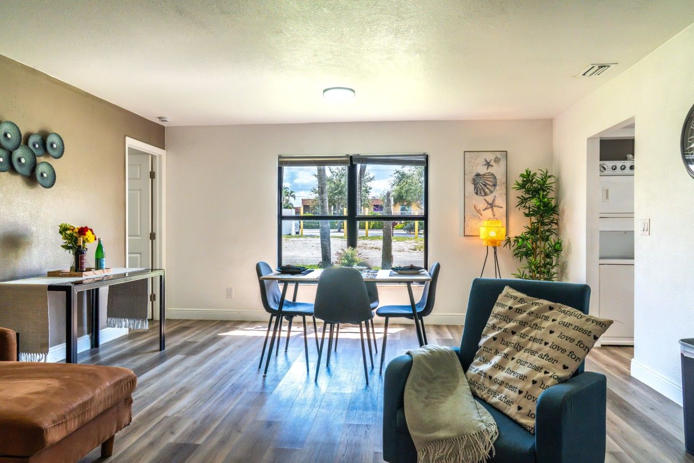 Open-Concept Dining & Living Area: Host memorable group dinners or work comfortably from home in this light-filled open-concept space, featuring a dedicated four-person dining set, comfortable accent seating, warm luxury vinyl plank flooring, and smooth f