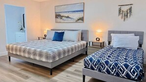 Een slaapkamer met twee bedden, een schilderij, een wanddecoratie en een deur.