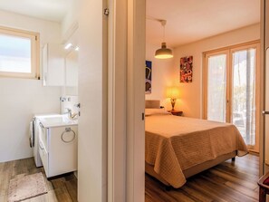 Ein Schlafzimmer mit einem Bett, einer Nachttischlampe, einem Fenster und einer Tür.