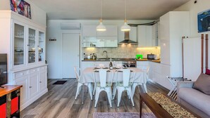 Una cocina moderna con armarios blancos, una mesa de comedor con sillas y un sofá en la zona de estar.