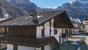 Ein Chalet mit geneigtem Dach, Holzbalkonen und einem Berg im Hintergrund.