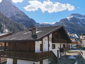 Ein Chalet mit geneigtem Dach, Holzbalkonen und einem Berg im Hintergrund.