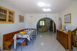 Ein Essbereich mit einem Tisch für vier Personen, einer Couch und einer Treppe.