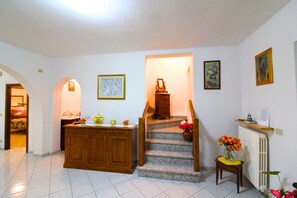 Eine Treppe führt zu einer zweiten Etage, ein Holzschrank mit Dekorationsobjekten und ein Heizkörper.