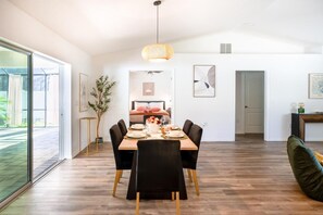 A dining area with a wooden table set for four, surrounded by black chairs, a hanging light fixture, and framed artwork on the walls. - Villa Summerfield - 3BR/2BT - Swim Spa/Hot Tub - 2mn from The Villages (Summerfield)