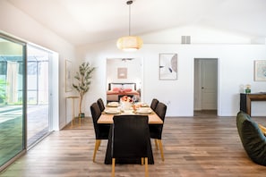 A dining area with a wooden table, black chairs, and a hanging light fixture.