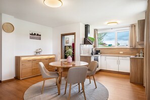 Une cuisine moderne avec des meubles en bois, une table de salle à manger ronde et des chaises.