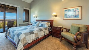 A bedroom with a large bed, a nightstand, a chair, a painting, and a balcony with a chair. - Beachfront condo w/ ocean views and 4 resort pools (Wailea-Makena)