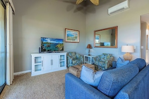 A living room with a sofa, a television, a cabinet, and a mirror. - Beachfront condo w/ ocean views and 4 resort pools (Wailea-Makena)