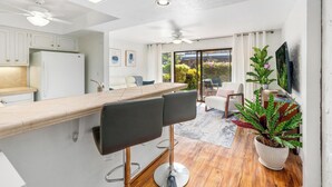 Une cuisine moderne avec un coin bar, un ventilateur de plafond et une vue sur l’extérieur.
