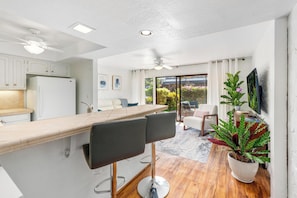 Eine moderne Küche mit Barbereich, Deckenventilator und Blick ins Freie.