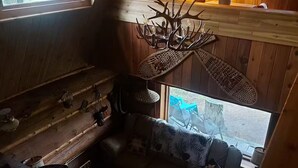A cabin interior with a loft bed, a chandelier, a sofa, and a dining table.