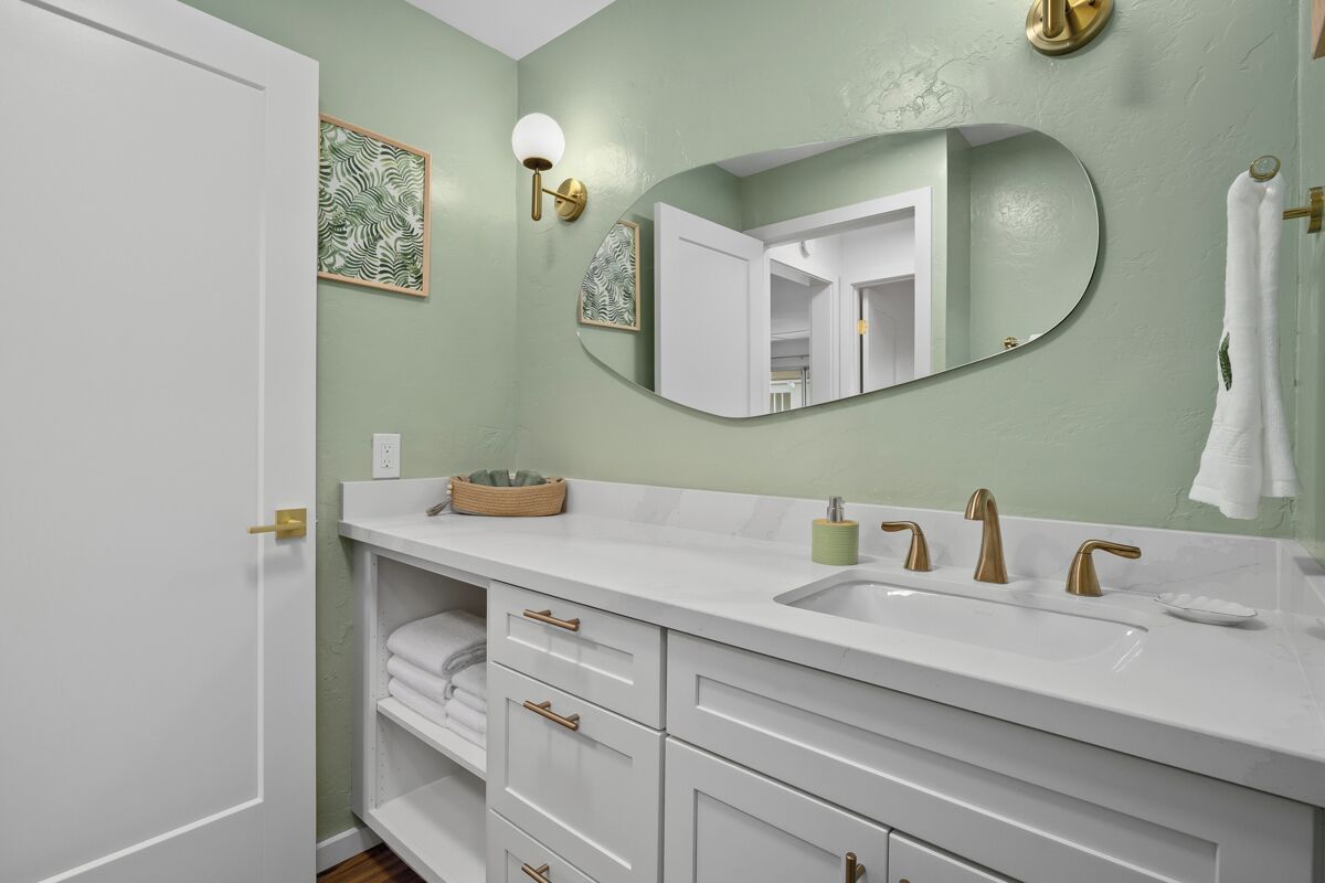 Une salle de bain avec un meuble-lavabo blanc, un grand miroir et un porte-serviettes.