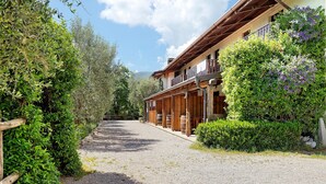 Un bâtiment avec un chemin de gravier, des balcons en bois et une végétation luxuriante.