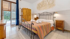Une chambre à coucher comprenant un lit, une armoire en bois, une table de chevet et une vue sur l’extérieur.