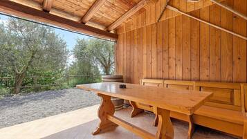 Un tavolo e una panca di legno in una zona esterna coperta, con vista sugli alberi.