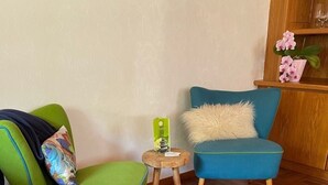 A room with a green armchair, a blue armchair, a small wooden stool, and a bed with white bedding. - The perfect time-out a small but fine accommodation in the heart of the Saarland? (Illingen)