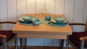 A dining table set with blue bowls and clear glasses, a hanging pendant light, and a wooden table against a paneled wall. - The perfect time-out a small but fine accommodation in the heart of the Saarland? (Illingen)
