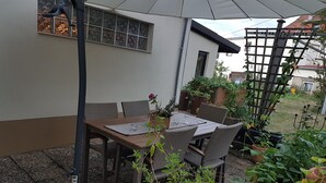 An outdoor patio with a table and chairs, surrounded by potted plants and a trellis. - The perfect time-out a small but fine accommodation in the heart of the Saarland? (Illingen)