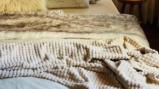 A bed with a textured blanket, a fluffy pillow, and a bedside table with a candle. - The perfect time-out a small but fine accommodation in the heart of the Saarland? (Illingen)