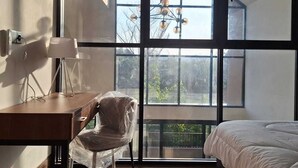 A bedroom with a large window, a desk, a chair, and a bed. - Via Adonia Mezzanine (Ungasan)