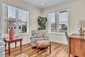 Sink into this cozy reading nook where colorful tropical prints meet warm wood tones, creating your perfect corner for relaxation. - Sound Views, Ocean Peeks + 2 Living Areas | Dogs OK | Walk to Beach (Emerald Isle)