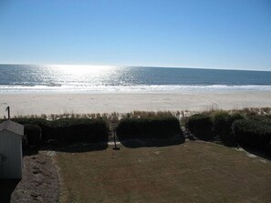 Blick auf einen Strand mit einer Rasenfläche und einem kleinen Gebäude.