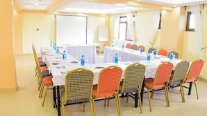 Un salón de conferencias con una larga mesa, sillas, botellas de agua y una pizarra.