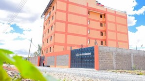 Un edificio de varios pisos con un llamativo letrero que dice 'HOTEL PARKING', fachada de ladrillo y entrada con portón.