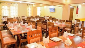 Un comedor con varias mesas y sillas, dispuestas en filas.
