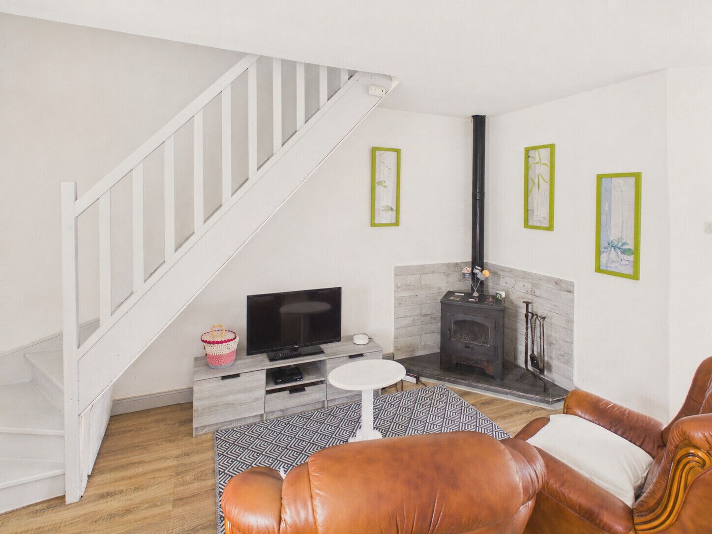 A living room with a TV, fireplace, and a staircase.