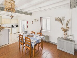 A dining area with a table set for four, wooden chairs, a kitchen in the background, and a radiator on the floor. - House with pool 50 m from Lascaux IV for four (Montignac)