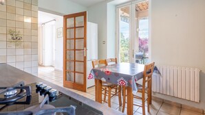 Een keuken met een eettafel, stoelen, een fornuis en uitzicht door een glazen deur.