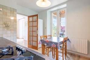 Una cocina con una mesa de comedor, sillas, estufa y vistas a través de un ventanal.