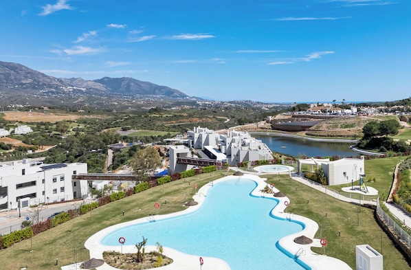 Ein modernes Hotel mit Schwimmbad, Blick auf die umliegende Landschaft und einem Wasserspiegel.
