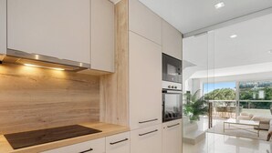 A modern kitchen with wood accents, a built-in oven, and a dining area with a view. - The Don | Terrace - Views - Pool (La Cala de Mijas)